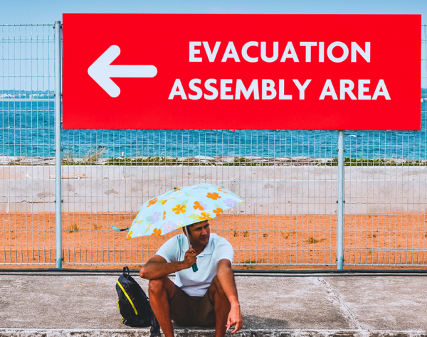 Man sitting under an evacuation sign