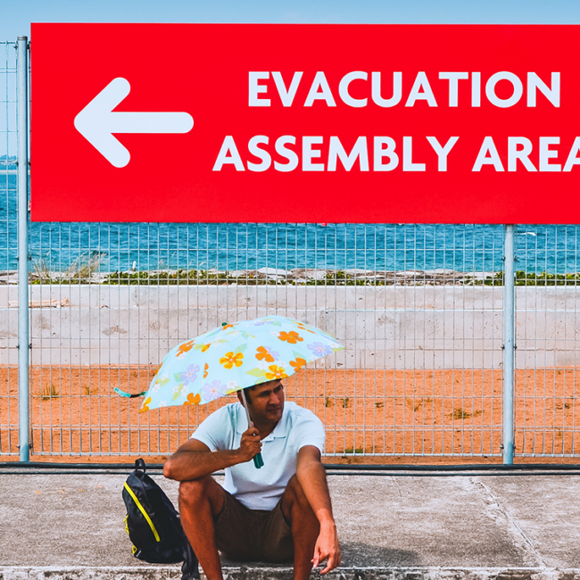 Man sitting under an evacuation sign
